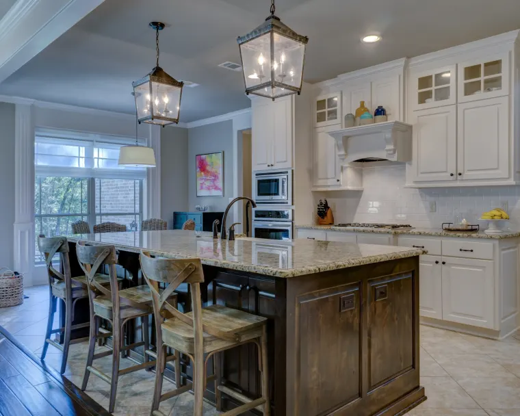 Custom kitchen with a stained timber island, white cabinetry and pendant lanterns