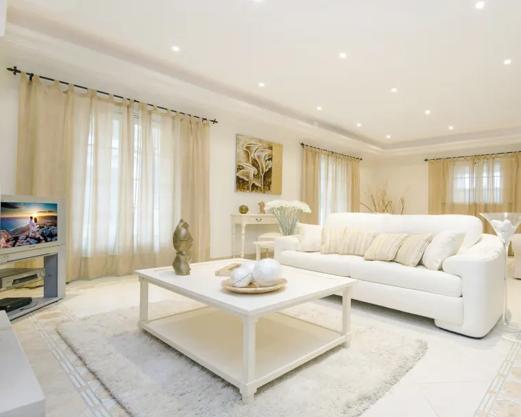 Formal living room with a cream sofa, coffee table and sheer floor-length curtains