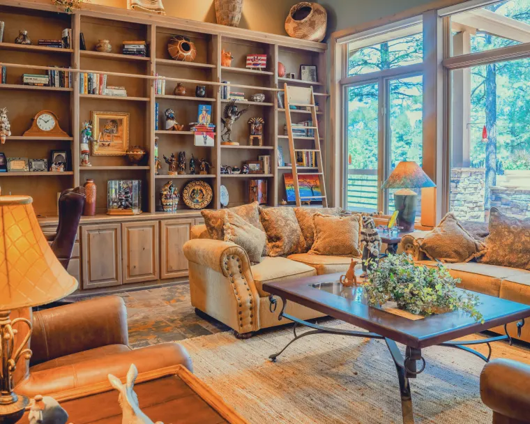 Warm timber built-in library shelving with a rolling ladder and tan leather seating
